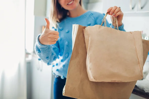 Elección bolsa de papel. Mujer eligiendo eco paquete en lugar de polietileno y mostrando el pulgar hacia arriba en la cocina en casa —  Fotos de Stock