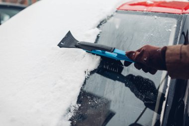 Süpürge kullanarak kardan araba temizliği. Otomobille ilgilenen adam dışarıda fırçayla buz kaldırıyor.