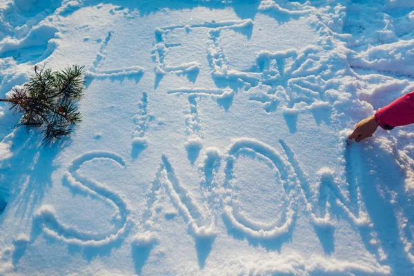 Let it snow writing on fresh snow made by woman outdoors. Winter frosty weather