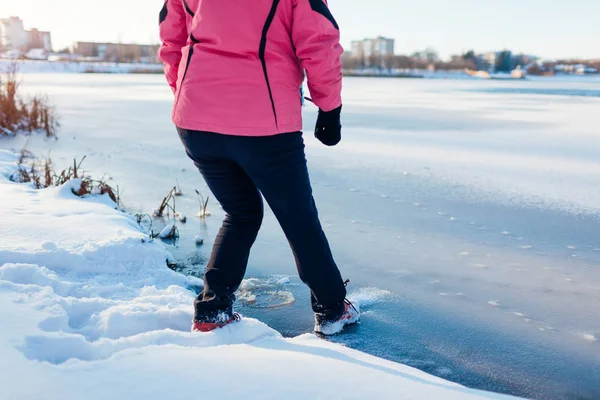 危险的薄冰 冬天，女人冒险踩在冰冻的河面上。 小心，不安全的水，下降的可能性 — 图库照片
