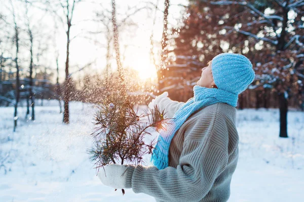 冬季季节性活动。 老年妇女在日落时分拿着冷杉树枝向空中扔雪 — 图库照片