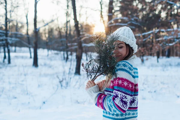 Paseo de invierno. Mujer joven sosteniendo ramas de abeto en el bosque disfrutando de clima nevado en suéter de punto — Foto de Stock