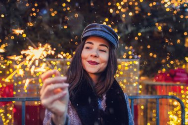 Noel, yeni yıl konsepti. Şehir panayırında Noel ağacında maytap yakan bir kadın..