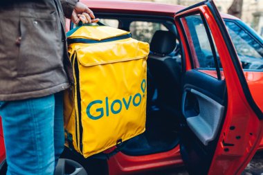 Lviv, Ukrayna 13 Ocak 2020 Glovo teslimat çantası. Erkek işçi termoçantayı otomatiğe koyar. Yiyecek dağıtım şirketi.