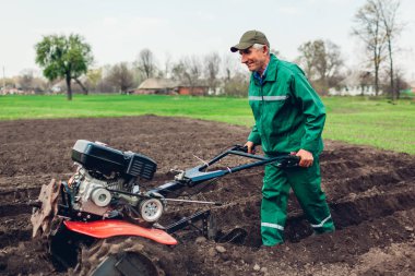 Çiftçi adam toprak ekimi ve patates ekimi için küçük traktör kullanıyor. Bahar hazırlığı