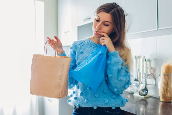 Elección de bolsa de plástico o papel. Mujer ama de casa elegir entre eco y paquete de polietileno en la cocina en casa —  Fotos de Stock