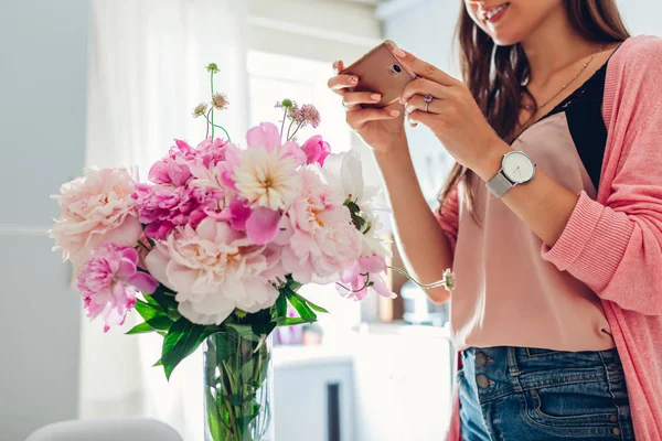 Frauentag, Valentinstag. Frau fotografiert Strauß von Pfingstrosen Blumen. Geschenk vom Ehemann — Stockfoto