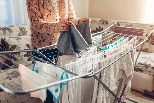 Mujer plegable recogiendo ropa limpia de la secadora después de lavarse en casa. Limpieza y tareas domésticas — Foto de Stock