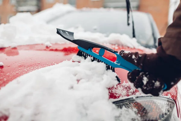 Auto reinigen van sneeuw met behulp van bezem. Man die zorgt voor auto verwijderen ijs met borstel buiten — Stockfoto