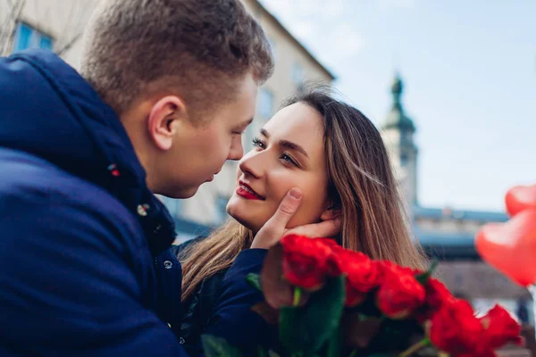 Alla hjärtans dag dejt. Man och kvinna på väg att kyssas utomhus. Par promenader med rosor blommor och ballonger — Stockfoto