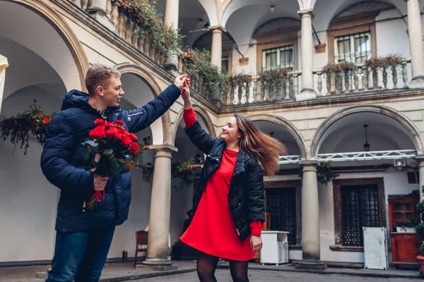 Ημέρα του Αγίου Βαλεντίνου ρομαντικό ραντεβού. Φίλος και φίλη χορεύουν. Ζευγάρι περπατά στην ιταλική αυλή στο Lviv με τριαντάφυλλα — Φωτογραφία Αρχείου