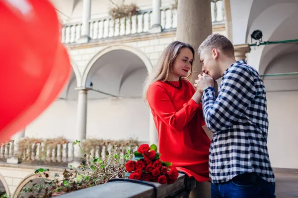 Walentynki romantyczna randka. Mężczyzna całujący się z dziewczyną. Para spacerująca po włoskim podwórku we Lwowie z różami — Zdjęcie stockowe