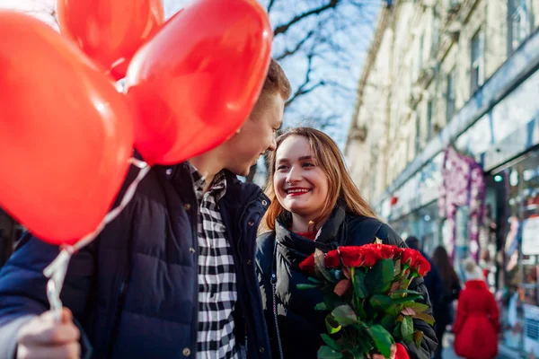 Το ερωτευμένο ζευγάρι του Αγίου Βαλεντίνου. Φίλος και φίλη περπάτημα με τριαντάφυλλα λουλούδια και μπαλόνια στην πόλη — Φωτογραφία Αρχείου