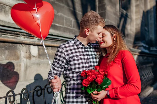 Walentynki zakochanej pary. Mężczyzna i kobieta przytulający się z bukietem kwiatów z balonami na ulicy miasta. — Zdjęcie stockowe