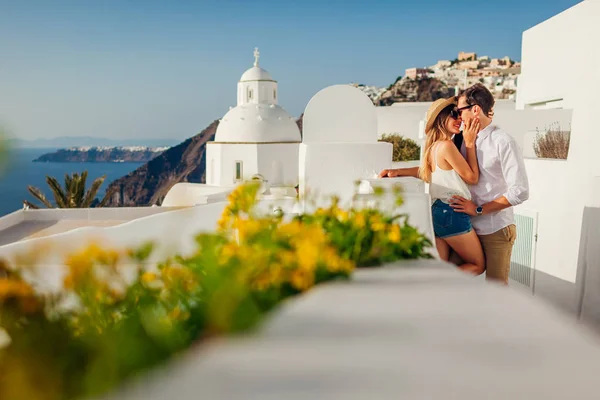 Santorini, Grecia luna de miel. Pareja enamorada caminando y besándose en Fira. Esposo y esposa disfrutando del paisaje marino . — Foto de Stock