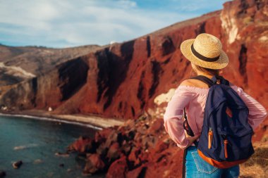 Yunanistan 'ın Santorini adasının Akrotiri kentindeki Kızıl Sahil manzarasına bakan bir turist. Seyahat eden bir kadın.