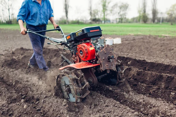 Farmář řídí malý traktor pro obdělávání půdy a pěstování brambor. Jarní zemědělská příprava — Stock fotografie