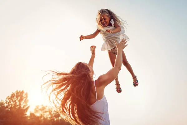 Dia da mãe. Mulher brincando e se divertindo com a filha no parque de verão. Mãe jogando menina ao ar livre . — Fotografia de Stock