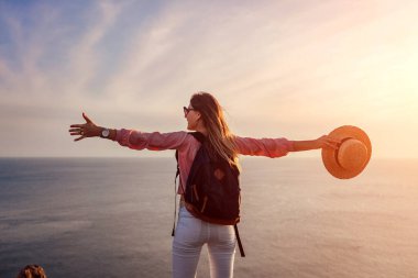 Gezgin yürüyüşçü Yunanistan 'ın deniz manzarasının tadını çıkararak Santorini adasındaki dağın zirvesine ulaştı. Sırt çantalı kadın mutlu bir şekilde kollarını kaldırdı. Yaz turizmi