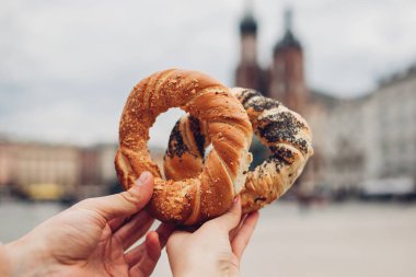 Krakow 'daki Market Meydanı' nda ellerinde obwarzanek simit, geleneksel Polonya mutfağı prezel aperatifleri tutan iki turist. Avrupa 'yı gezmek