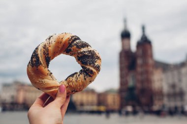 Krakow 'daki Market Meydanı' nda ellerinde simit, geleneksel Polonya mutfağı prezel atıştırmalıkları olan turistler. Avrupa 'yı gezmek