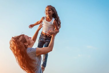 Anneler Günü. Bahar parkında kızıyla oynayan bir kadın. Anne kızı dışarı atıp gülüyor. Aile zamanı. Boşluk