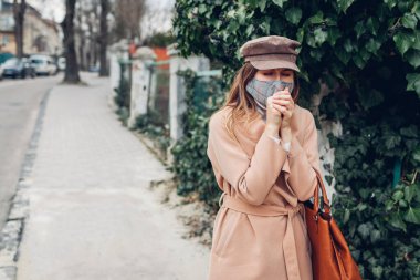 Öksüren kadın Coronavirus covid-19 salgını sırasında dışarıda yürürken tekrar kullanılabilir maske takıyor. Grip salgılayan bir kız. Dikkatli olun, uzak durun.