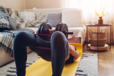 Koronavirüs karantinası sırasında evde egzersiz. Kalça kasları gelişiyor. Kalça köprüsü. Kemerli halterle kadın eğitimi.