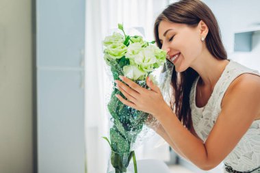 Bir buket Eustoma çiçeği kokan bir kadın. Ev hanımı, Coronavirus karantinasında mutfağın içini ve dekorunu beğeniyor. Güzel ev.