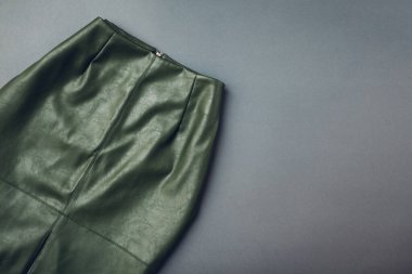 Gri arka planda moda deri etek. Bahar kadın kıyafetleri. Ekolojik malzemeden yapılmış zarif yeşil etek. Moda. Boşluk