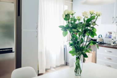 Anneler günü hediyesi. Mutfakta bir buket beyaz gül. Modern mutfak tasarımı. Mutfağın içi çiçeklerle süslenmiş. Konforlu daire