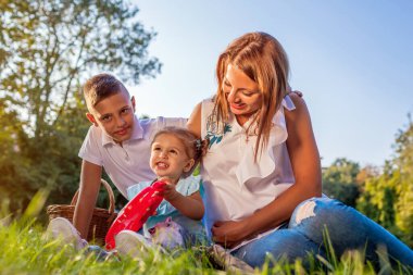 Anneler Günü. Mutlu aile dışarıda parkta çimlerin üzerinde oturarak vakit geçiriyor. İki çocuklu bir anne ve gülümseyen bir kız çocuğu. Aile değerleri