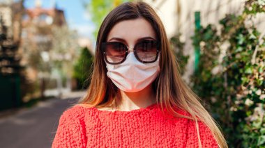 Coronavirus covid-19 salgını sırasında kadın dışarıda koruyucu maske takıyor. Kız tek başına kameraya bakıyor.