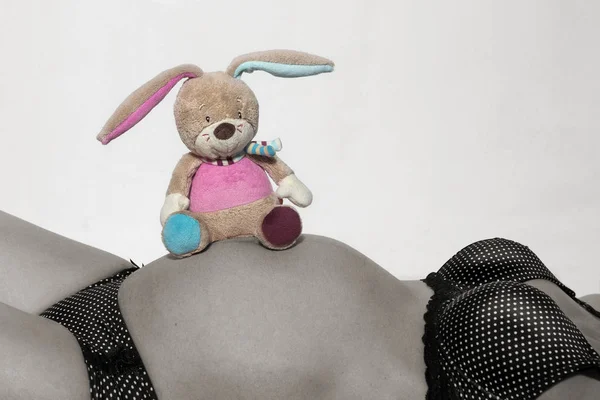 Barriga do bebê com pequeno brinquedo de pelúcia — Fotografia de Stock