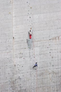 Baraj duvarına tırmanıyor.