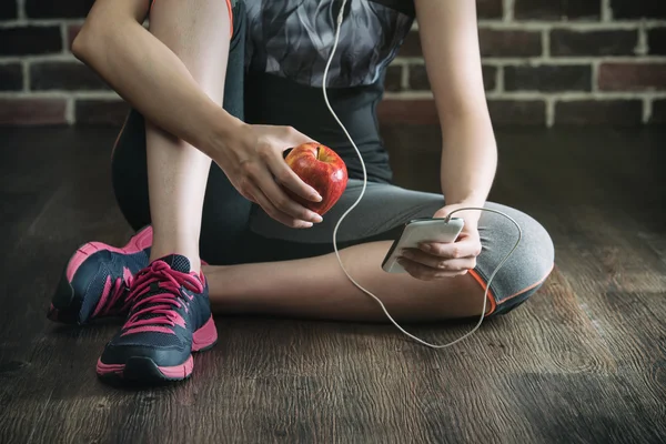Odpocząć, słuchając muzyki jedzenia apple po ćwiczenia fitness — Zdjęcie stockowe