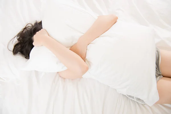 Beautiful asian woman feel unwell painful and holding pillow — Stock Photo, Image