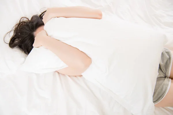 Красивая азиатская женщина чувствовать себя нехорошо болезненно и держа подушку — стоковое фото