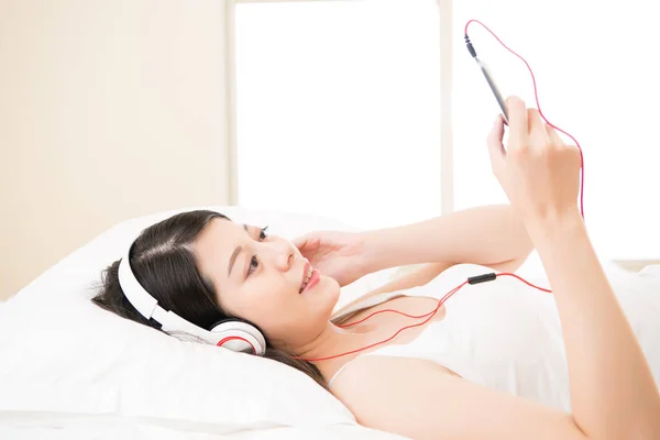 Mujer asiática escuchar música buscando teléfono inteligente con auriculares —  Fotos de Stock