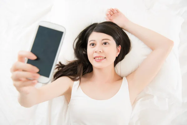 Hermosa mujer asiática tomar selfie con smartphone en la cama — Foto de Stock