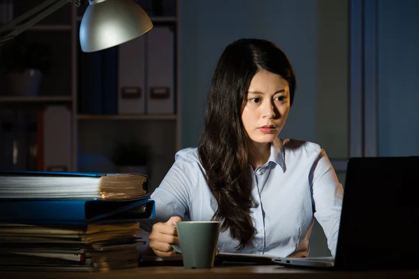 Азиатская деловая женщина пьет кофе, работая сверхурочно поздно ночью — стоковое фото