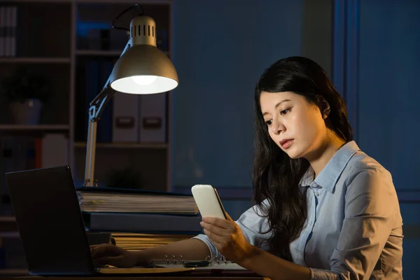 Азиатская бизнес-женщина текстовое сообщение на смартфоне работает сверхурочно — стоковое фото