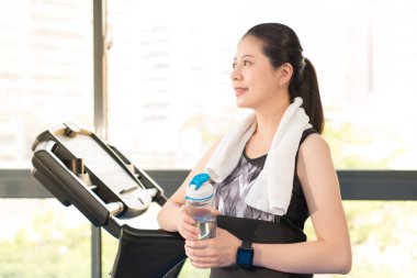 Koşu bandı sonra su şişesi tutan güzel Asyalı kadın dinlenme