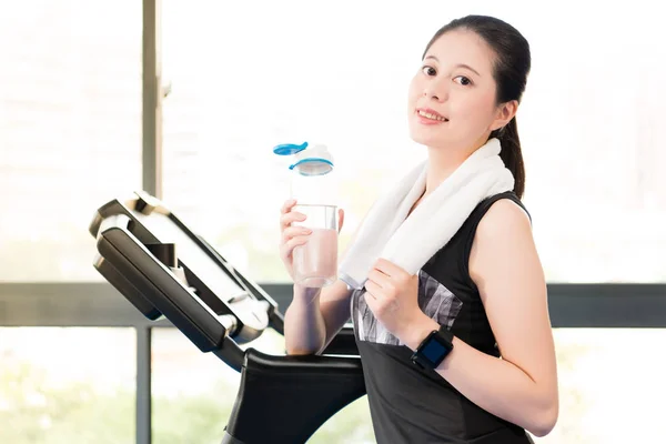 Beautiful asian woman rest holding water bottle after treadmill — Stock Photo, Image