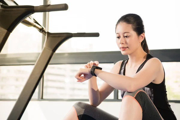 Asiatisk kvinna resten på löpband använda smartwatch kontrollera puls — Stockfoto