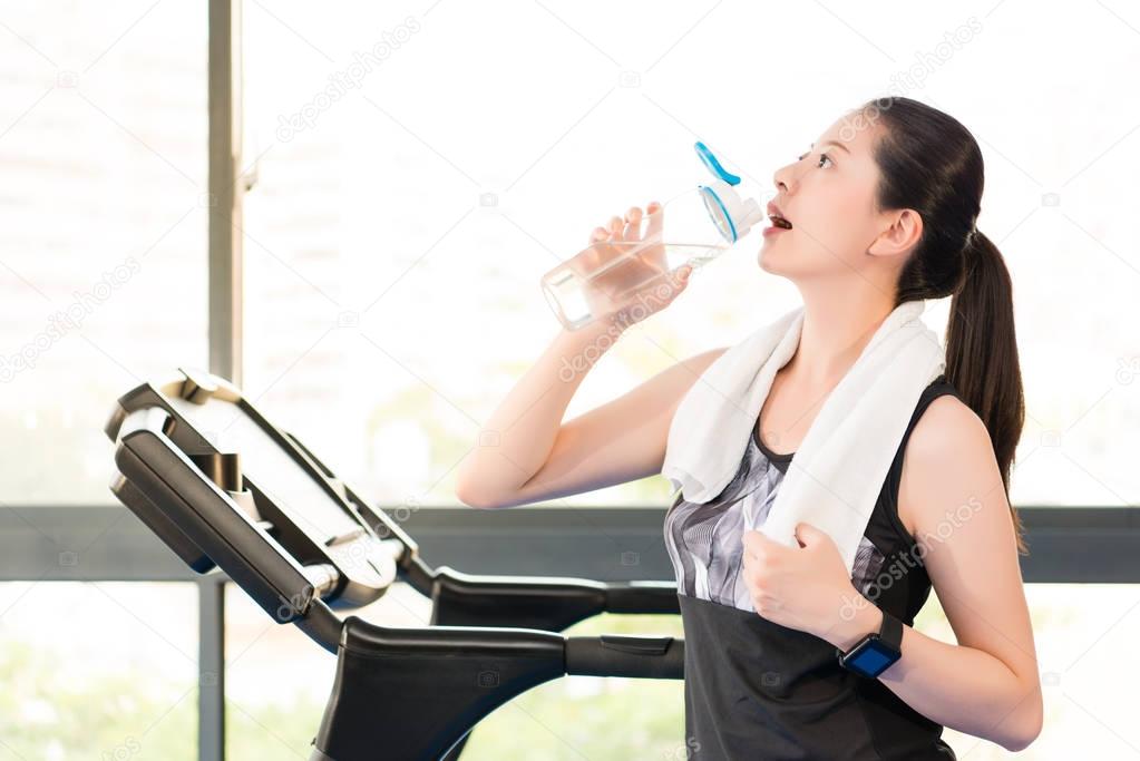 Beautiful asian woman rest drinking water bottle after treadmill