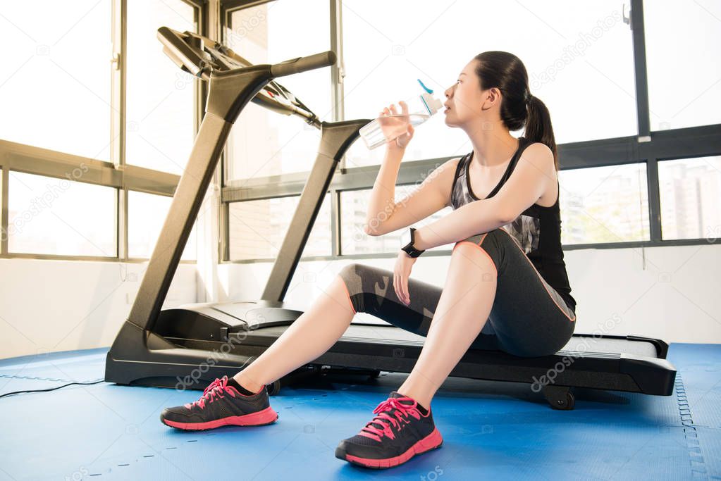 sport woman rest on treadmill use smartwatch drinking water
