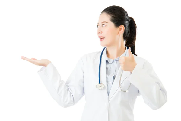 S úsměvem Asijské žena lékaře zobrazit něco a palec nahoru — Stock fotografie