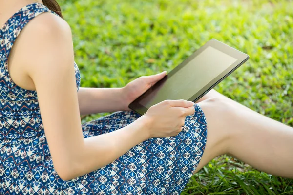 Beauty asian woman using digital tablet sitting on grass — Stock Photo, Image