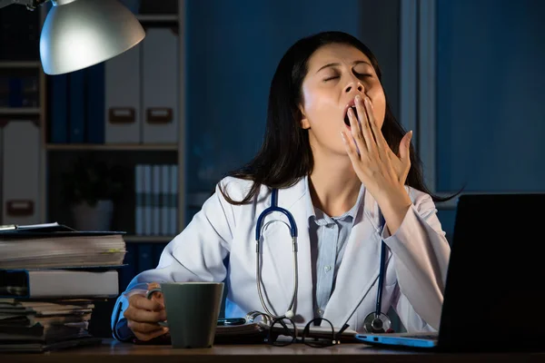 Doctor sentado en el escritorio y bostezando en el hospital — Foto de Stock